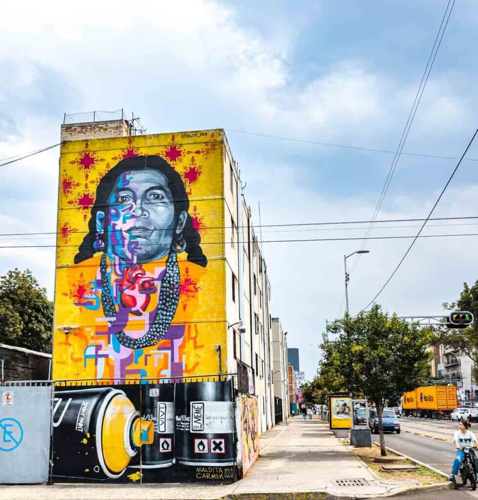 «نقاشی دیواری مکزیک با رنگهای درخشان و جزئیات دقیق که گوشهای از فرهنگ و زندگی مردم مکزیک را نشان میدهد؛ اثری از هنر خیابانی که در آن نمادهای سنتی، چهرههای بومی، و عناصر طبیعت در کنار هم قرار گرفتهاند و روح پرشور و آزاد مردم مکزیک را به تصویر میکشند.»